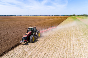Tractor harrownig the large brown field