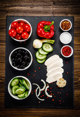 Vegetables for salad on black stone plate wooden background