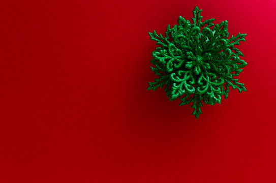 Close-up Of A Green Snowflake Ornament On The Up-right Corner Of A Red Background