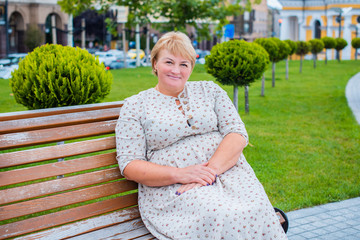 Portrait of attractive plus size mature woman in casual style walk at city at good sunny autumn day and thinking about something. Life of women after 40-50 years 