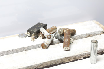 Used finger-wound batteries covered with corrosion. They lie on a wooden box. Recycling.