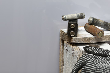 Used finger-wound batteries covered with corrosion. They lie on a wooden box. Next working gloves. Recycling.