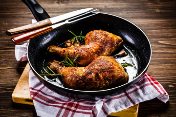 Fried chicken legs in pan on wooden table