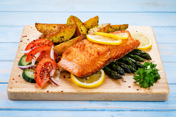 Grilled salmon with baked potatoes, asparagus and vegetable salad