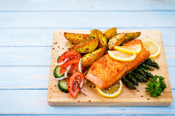 Grilled salmon with baked potatoes, asparagus and vegetable salad