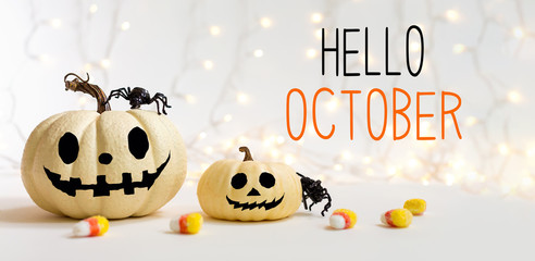 Hello October message with halloween pumpkins with spider on a shiny light background