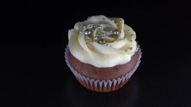 Fragrant, vanilla capcake with berry filling and honey cream cheese on black background, close up, rotates
