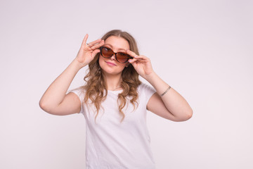 Beautiful white curly young woman wearing white t-shirt and sunglasses on white background