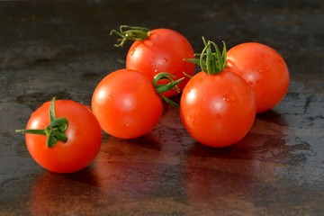 Red cherry tomatoes on a dark blue background.