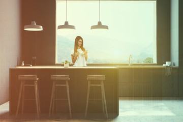 Woman in gray kitchen with bar and stools