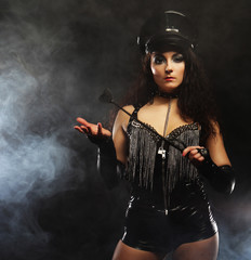 Sexy brunette woman mistress holding whip,over dark backgrouynd with smoke - obrazy, fototapety, plakaty