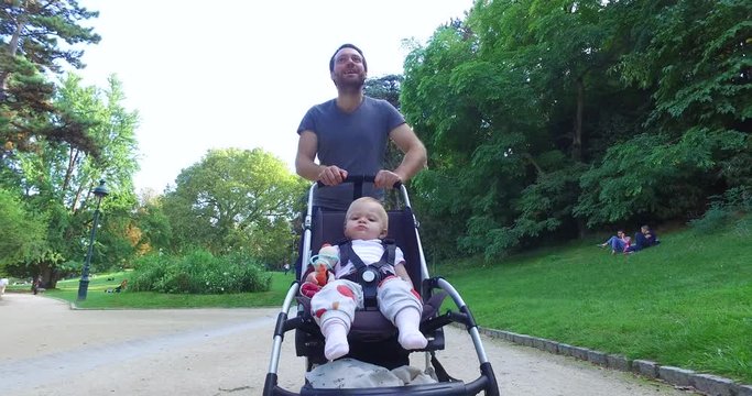 Medium shot of baby boy enjoying pram ride along with his father in park