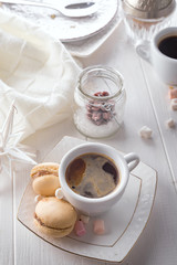 Tasty sweet macarons and coffee cup on white wooden background. Cristmas concept lazy morning, warm winter mood