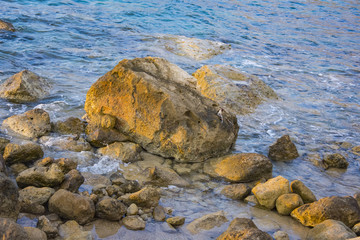 Landscape of the sundown in sea water amongst rocky beach