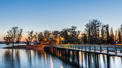 bridge leading to the island with wooden cottages illuminated by evening illumination. evening scene.
