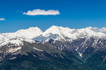 Fototapeta na wymiar Snowy mountain tops with clouds in the blue sky