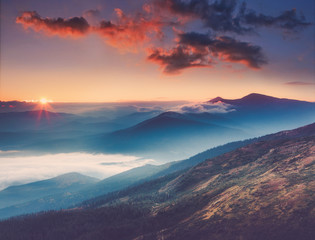 Amazing landscape in the mountains at sunrise. View of foggy hills covered by forest. Concept of...