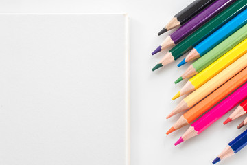 notepad with color pencil on white table view from above