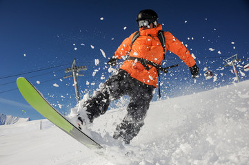 Snowboarder riding down the powder mountain hill on sunny day. Snowboarding in Georgia, Goderdzi