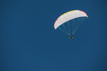 Skydiver under a canopy of a parachute against a blue sky in Georgia, Gudauri