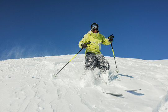 Smiling skier in yellow sportswear riding down the slope in Georgia, Gudauri
