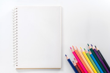 notepad with color pencil on white table view from above