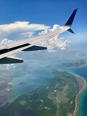 Freedom: Aerial view from above the clouds with a wing of an airplane in the sky over Cuba approaching the city of Havana (scenic journey over the ocean with beautiful view and cloudscape)