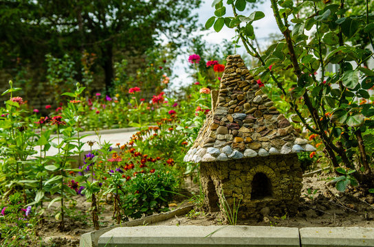 A small stone house for gnomes in a flower bed among the flowers. fairytale house