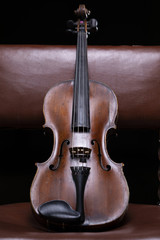 A violin or a viola resting on a vintage chair