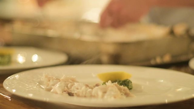Chef preparing and decorating fish, many round plates&nbsp;with meal in kitchen in restaurant

