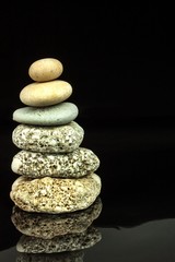 Pyramid of pebbles on a black background. Stones on the table. Wellness concept. Sea stones.