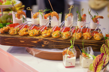 Cocktail Reception at the event, with dry ice Shrimps, burgers, salads, seafood on wooden boards, with sprouted greens