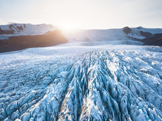 Glacier surface details viewed from above with crevasses and seracs, drone aerial view of...