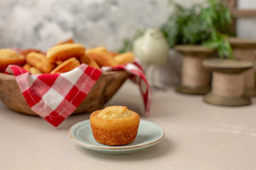Wooden Bowl of Cornbread Muffins, Sticks, and Slices on a Kitchen Table; Bowl Lined with Red and White Checked Napkin