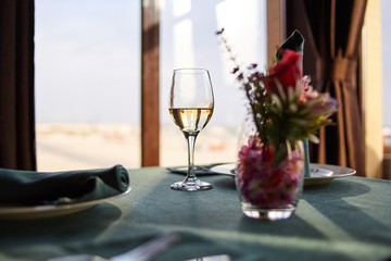 a glass of white wine is on the table on the background of the view from the window