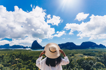 Asian woman traveler wearing a white shirt holding hat and looking at Samed Nang Chee amazing...