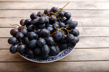 Plate of grapes closeup isolated on a rustic wooden table 