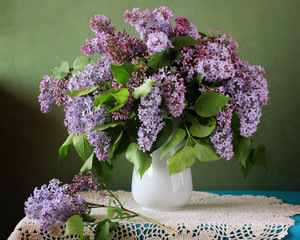 Bouquet of purple lilac in a vase on the table.