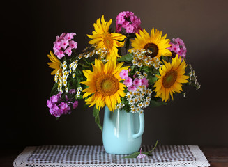 Bouquet of garden flowers: sunflowers, Phlox and daisies in a jug on the table.