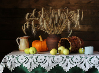 Still life in a rustic style with rye spikelets, apples and pumpkin.
