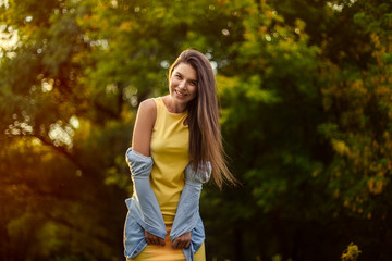 happy girl on a background of  trees. The girl laughs and rejoices in yellow dress.