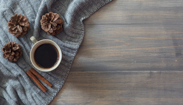 Winter background with knitting plaid, pine cones and cup of coffee