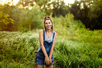 girl in headphones dancing in denim overalls. Out in the park.