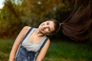 Portrait of a girl in headphones. Sport and healthy lifestyle, jogging on the street. Long and healthy hair, a wave of his head, flying hair.