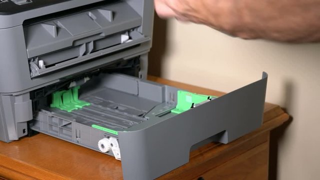 Businessman replacing paper inside laser printer in the office