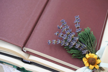 Open cover of book with small bunch of lavender, dry sunflower and green branches
