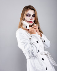 girl in a white coat on a white background with Halloween makeup