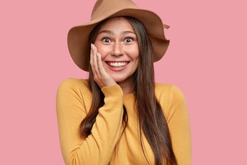Portrait of happy overjoyed girl with appealing appearance, gazes with broad smile, has fun,...