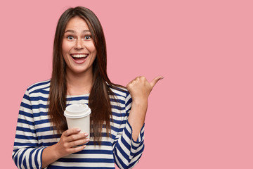 Indoor shot of pleasant looking positive woman with satisfied expression, spends free time with...