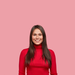 Fototapeta premium Vertical shot of beautiful young successful female architect has bright smile and dimple on cheek, recieves phone call from guy, poses over pink studio wall. People, facial expressions concept